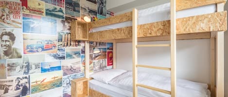 A bunk bed room with a wall decorated with various posters.