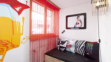 A room with a wooden bench, red curtains, a framed picture, and a wall with a colorful mural.