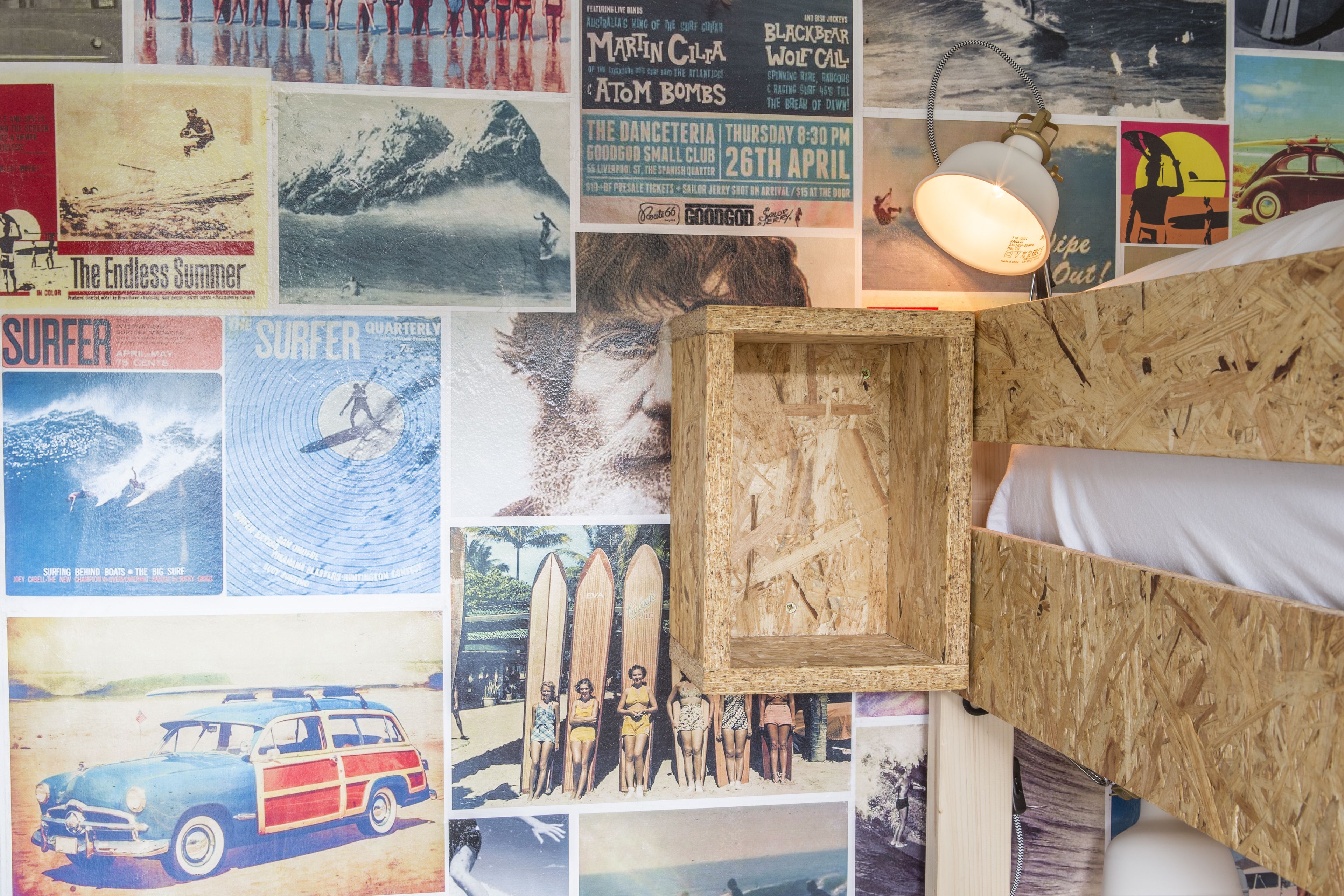 A room with a bed, posters on the wall, and a wooden headboard.