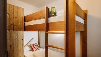 A bunk bed with a wooden headboard, a lower bed with a pillow, and a book on the top bunk.