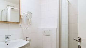 Un baño con lavamanos, espejo, secador de pelo y ducha.