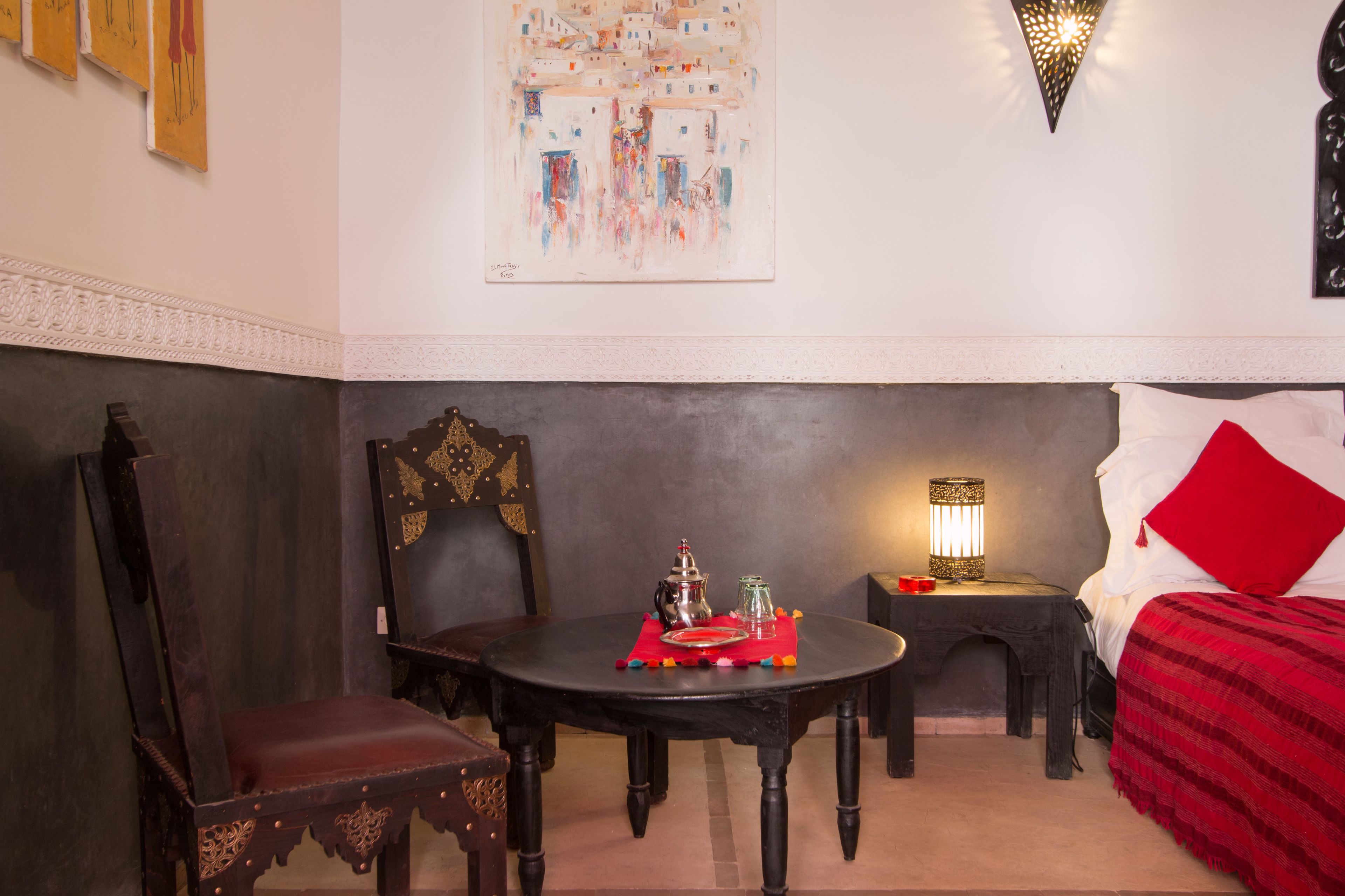 Una habitación con una cama, una mesa con una lámpara y una silla.
