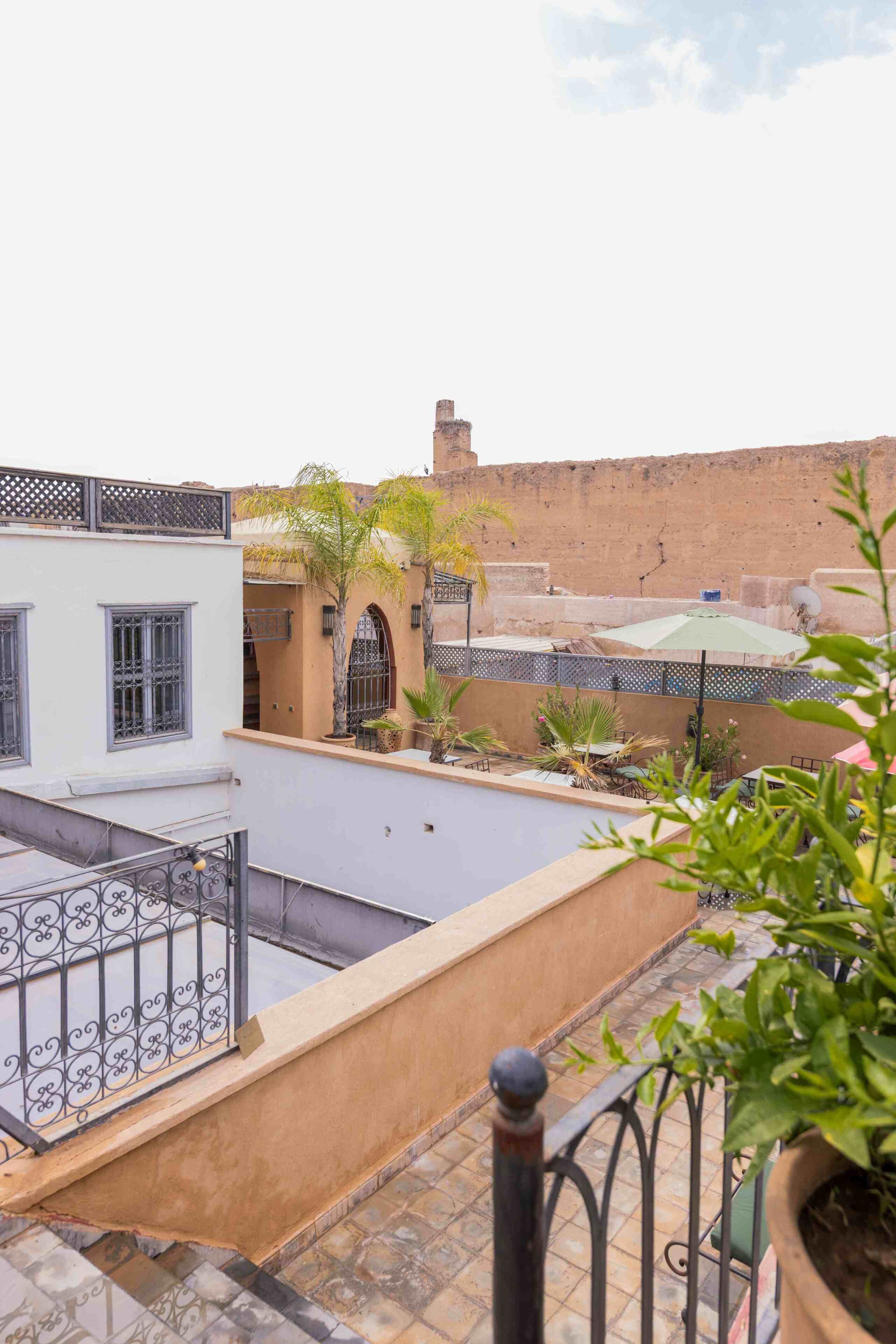 A rooftop terrace with a pool, a view of a traditional building, and a clear sky.