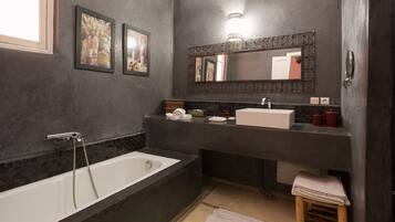 A modern bathroom with a bathtub, a sink, and a mirror.
