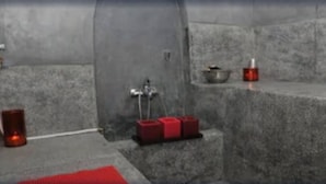 Une pièce avec un sol en béton, un évier en métal, une serviette rouge et une bougie rouge.