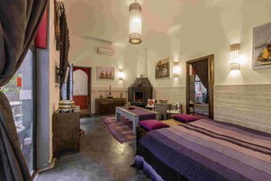 Una habitación con cama, una mesita, un espejo y chimenea.
