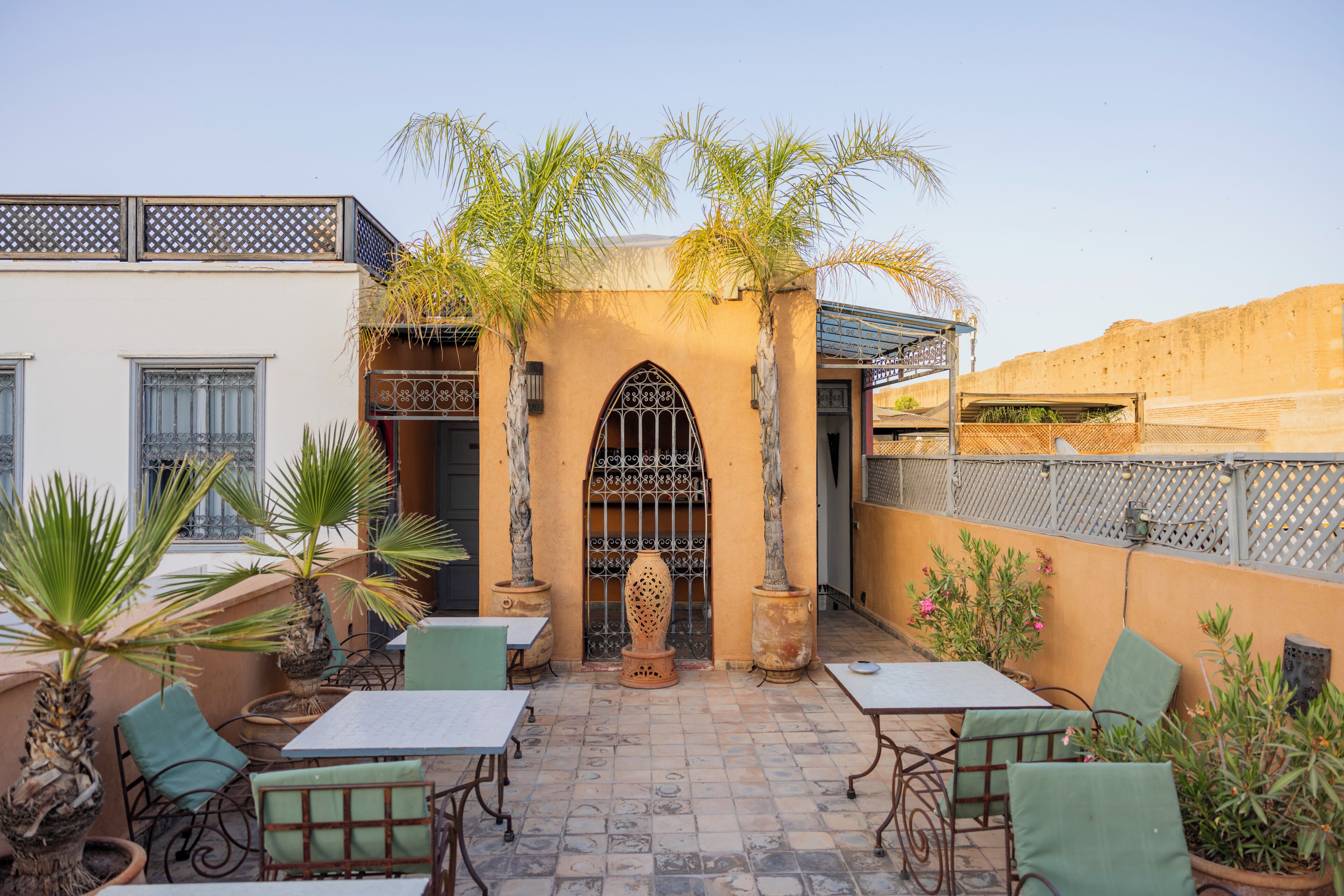 Un espacio al aire libre con patio amoblado, plantas en macetas y un arco decorativo.