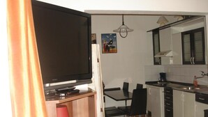 A compact kitchen with a dining area, a TV on a stand, and a small table with chairs. - Pension Easy Journey (Prague)