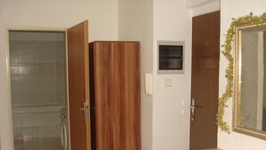 A bathroom with a toilet, a shower, and a wooden wardrobe. - Pension Easy Journey (Prague)
