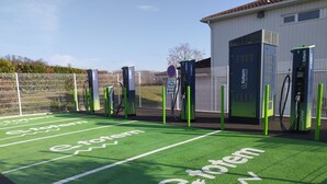 Un estacionamiento con marcas verdes y estaciones de carga para vehículos eléctricos.