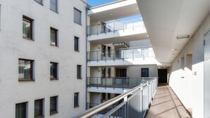 Un edificio de varios pisos con balcones, un corredor central y una escalera.