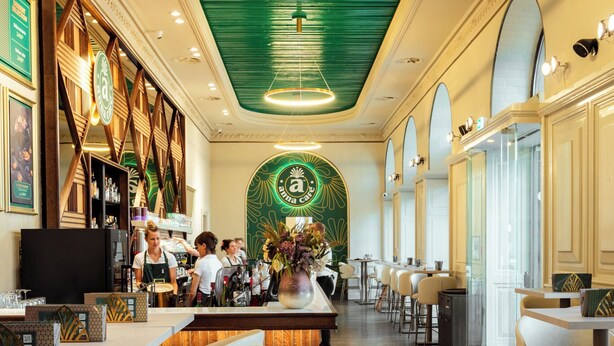 Interior de restaurante con barra, asientos y techo verde.