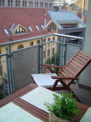 A balcony with a wooden chair, a small table, and a potted plant. - Trendy Deluxe Apartments (Budapest)