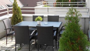 Un patio al aire libre con una mesa, sillas, una planta en maceta y un árbol pequeño.