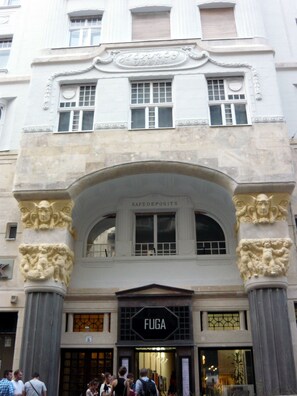Un bâtiment doté d’une grande entrée en arc de cercle, d’une enseigne indiquant « DÉPÔTS-CAISSE » et d’une autre enseigne, « FUGA », en dessous.