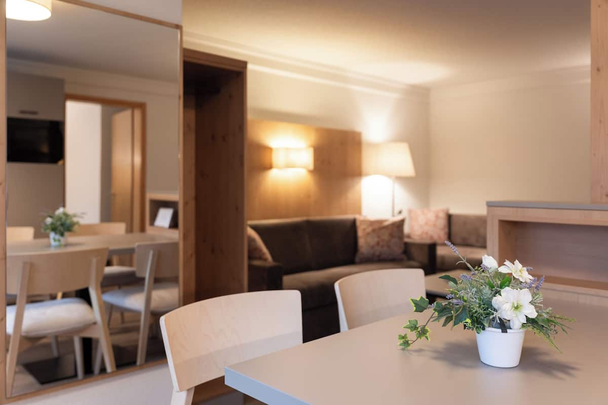 Uma sala de estar moderna com área de jantar, um sofá e uma mesa com planta em vaso.