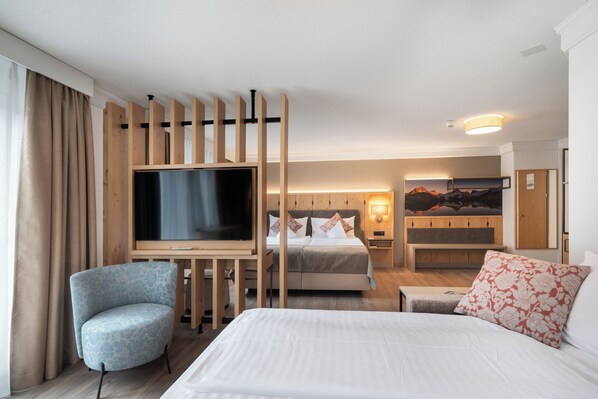 A hotel room with a bed, a TV, a chair, a desk, and a painting on the wall. - Grindelwalderhof (Grindelwald)