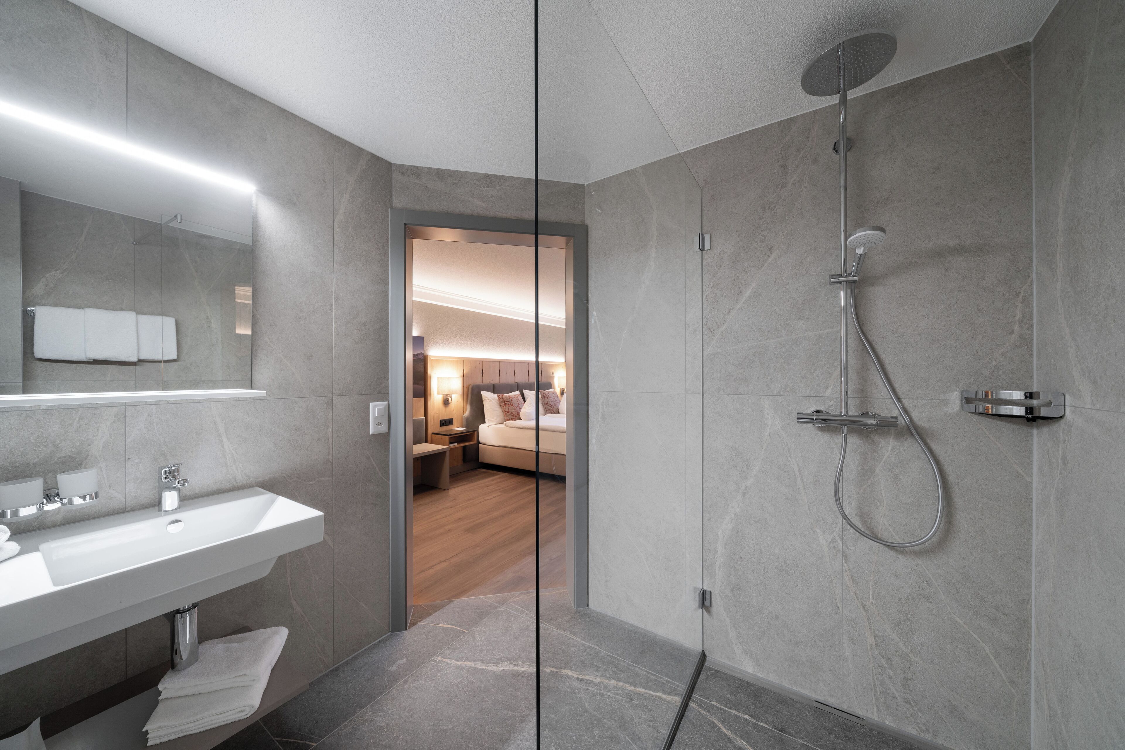 A modern bathroom with a glass partition, a shower, and a sink.