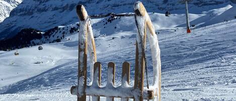 Un banco de madera cubierto de nieve con montañas al fondo.