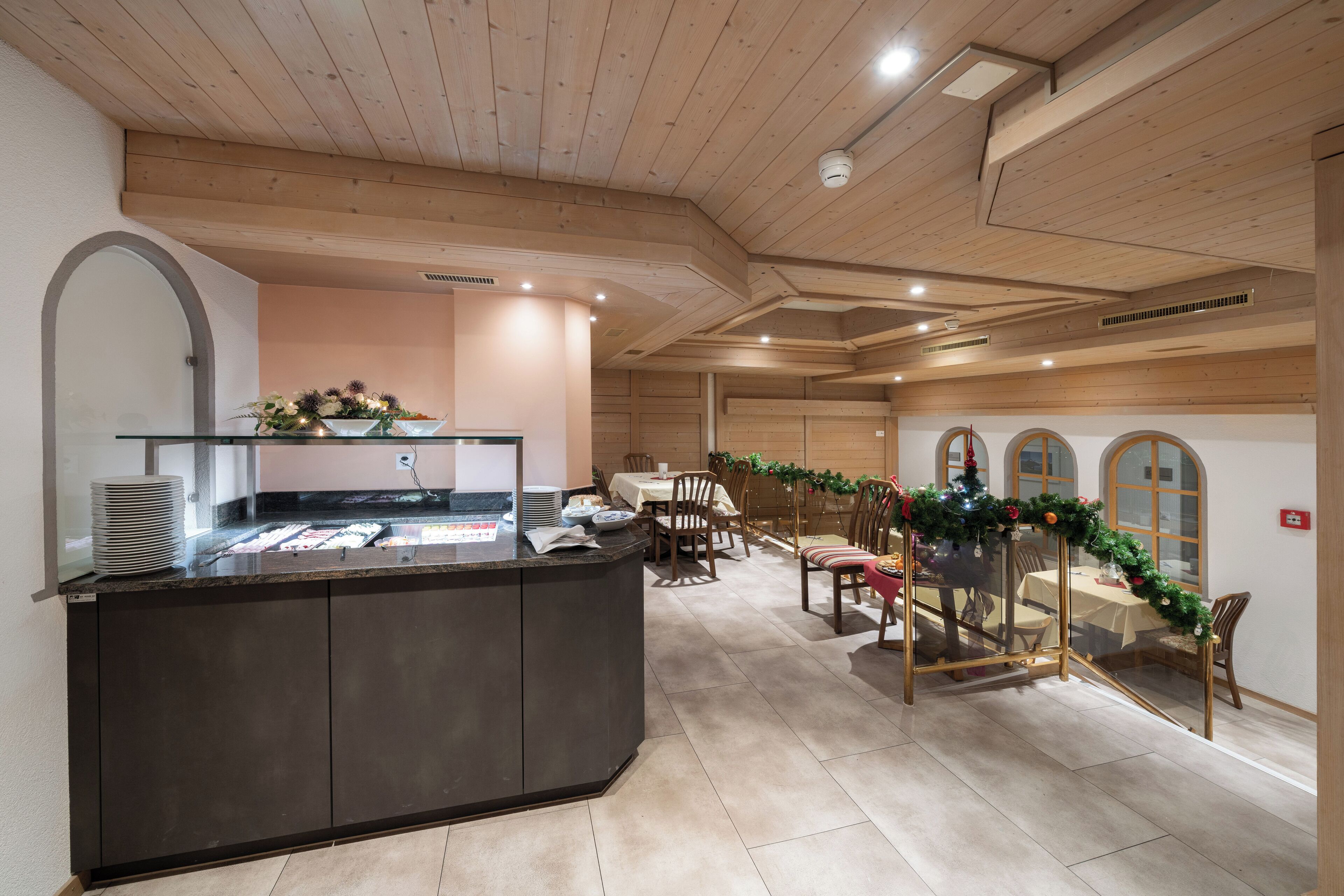 Un restaurante con una isla central tipo mostrador, techo de madera y un área de comedor con mesas y sillas.