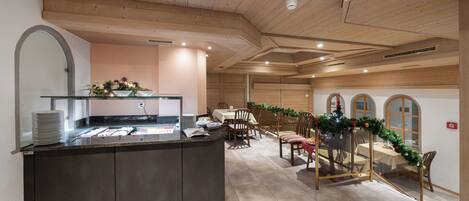 A restaurant with a central island counter, wooden ceiling, and a dining area with tables and chairs.