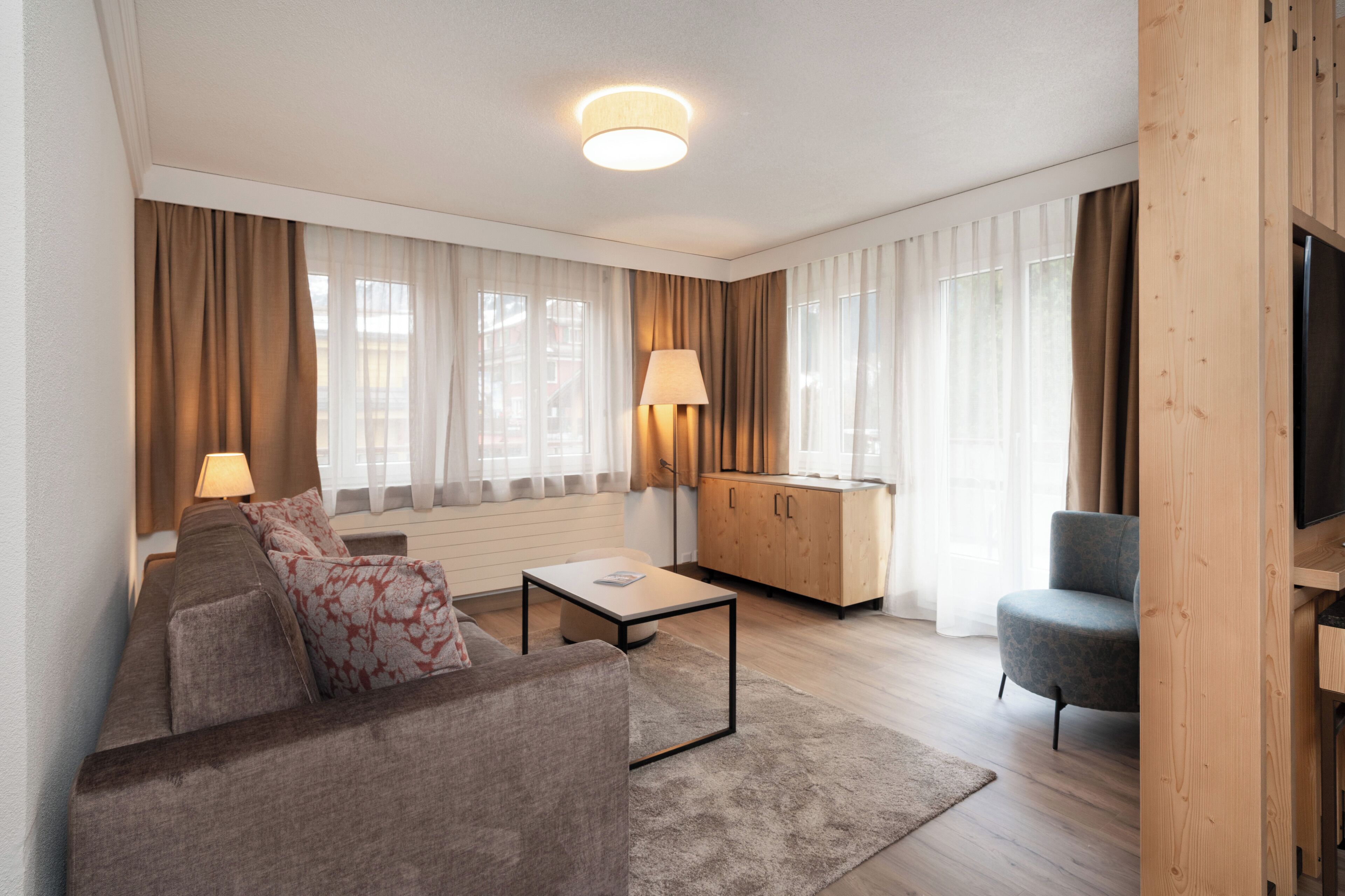 Un salon moderne comprenant un canapé, une table basse, une lampe, un téléviseur et un meuble en bois.