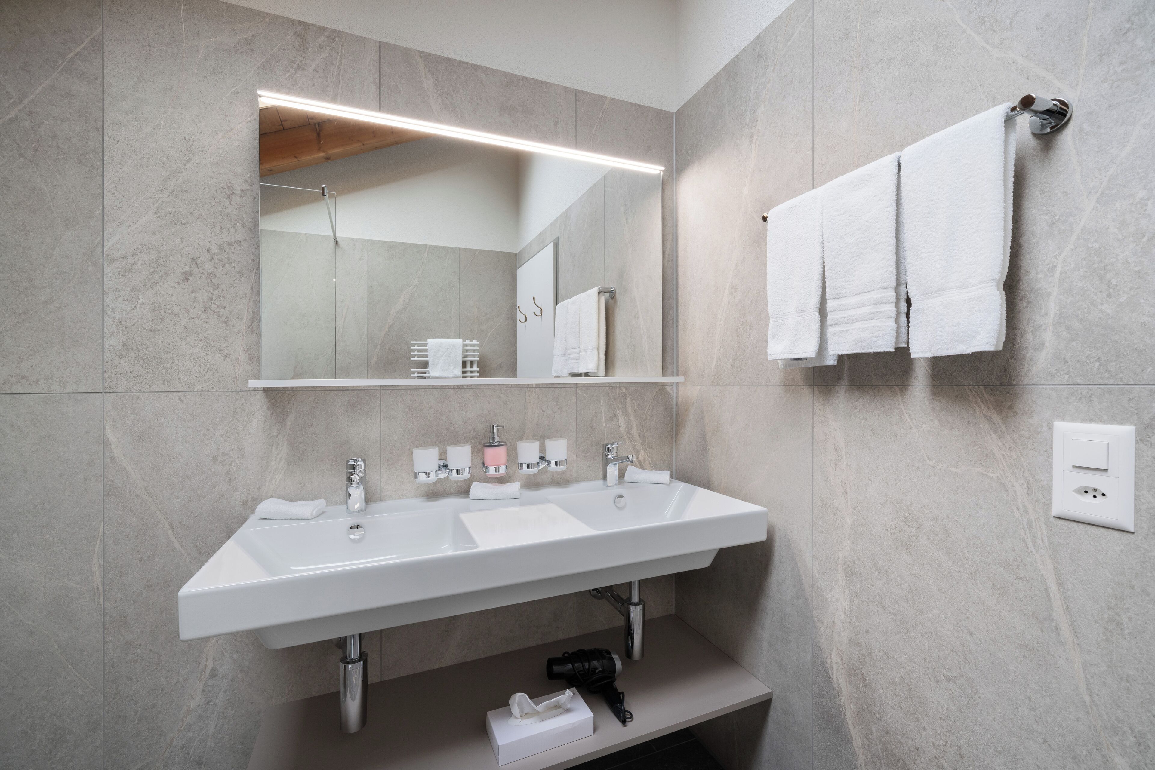 A modern bathroom with a double sink, a large mirror, and a towel rack.