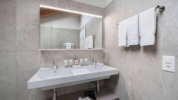 A modern bathroom with a double sink, a large mirror, and a towel rack.