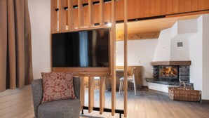 A modern living room with a large flat-screen TV, a fireplace, wooden beams, and a cozy seating area. - Grindelwalderhof (Grindelwald)