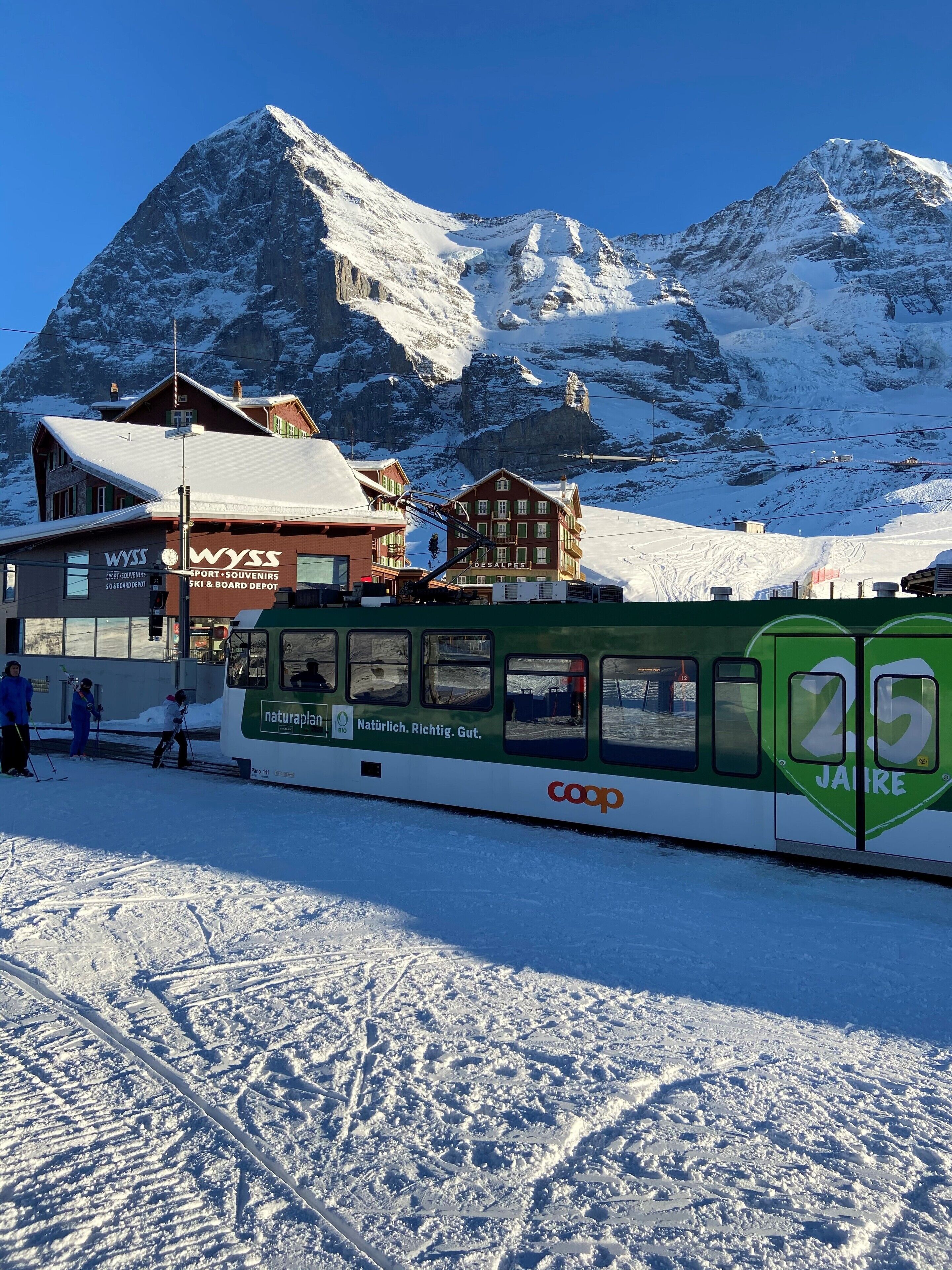 A snow-covered mountain with a ski resort building and a green tram.
