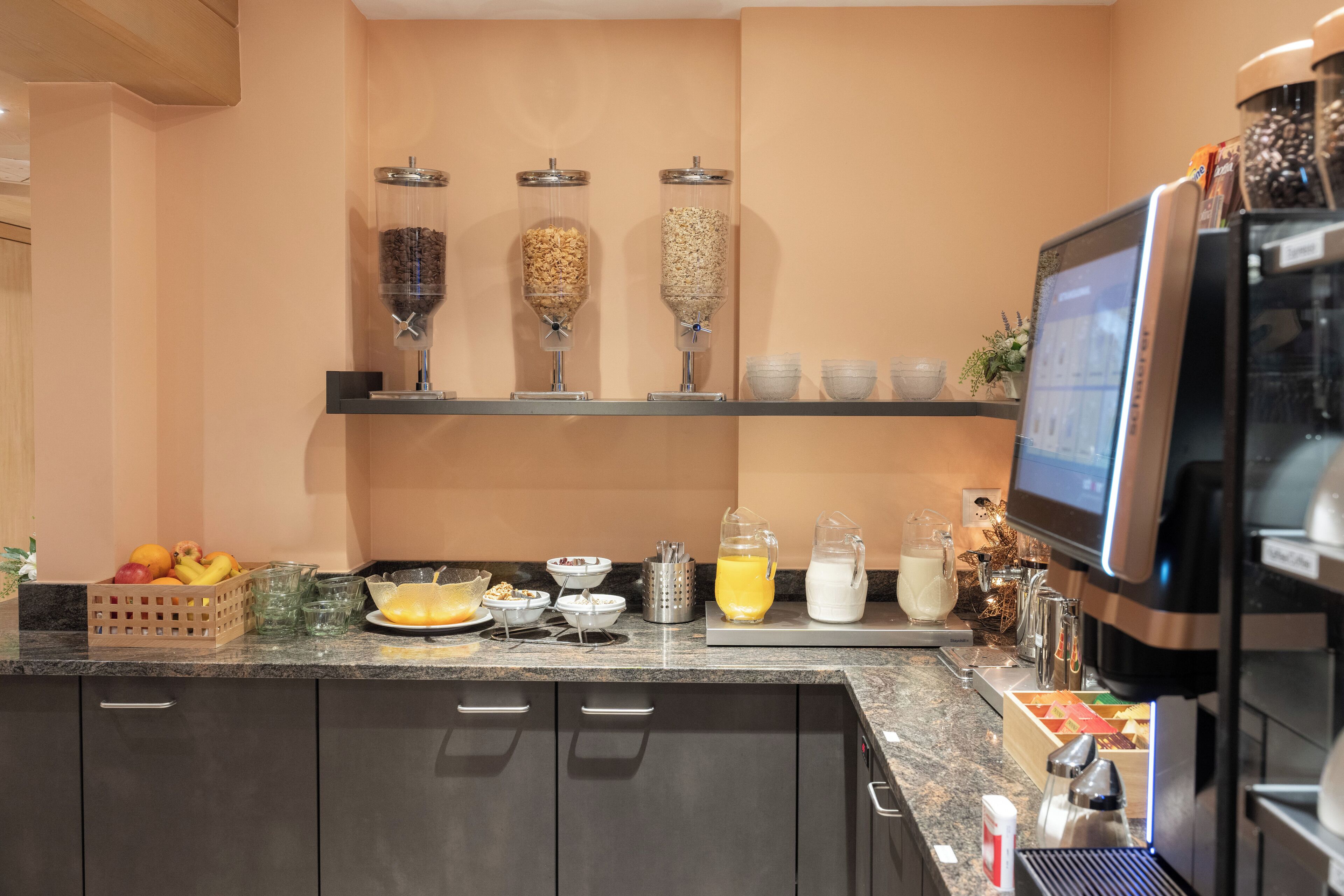 A modern kitchen with a coffee machine, a fruit bowl, and a coffee bean dispenser.