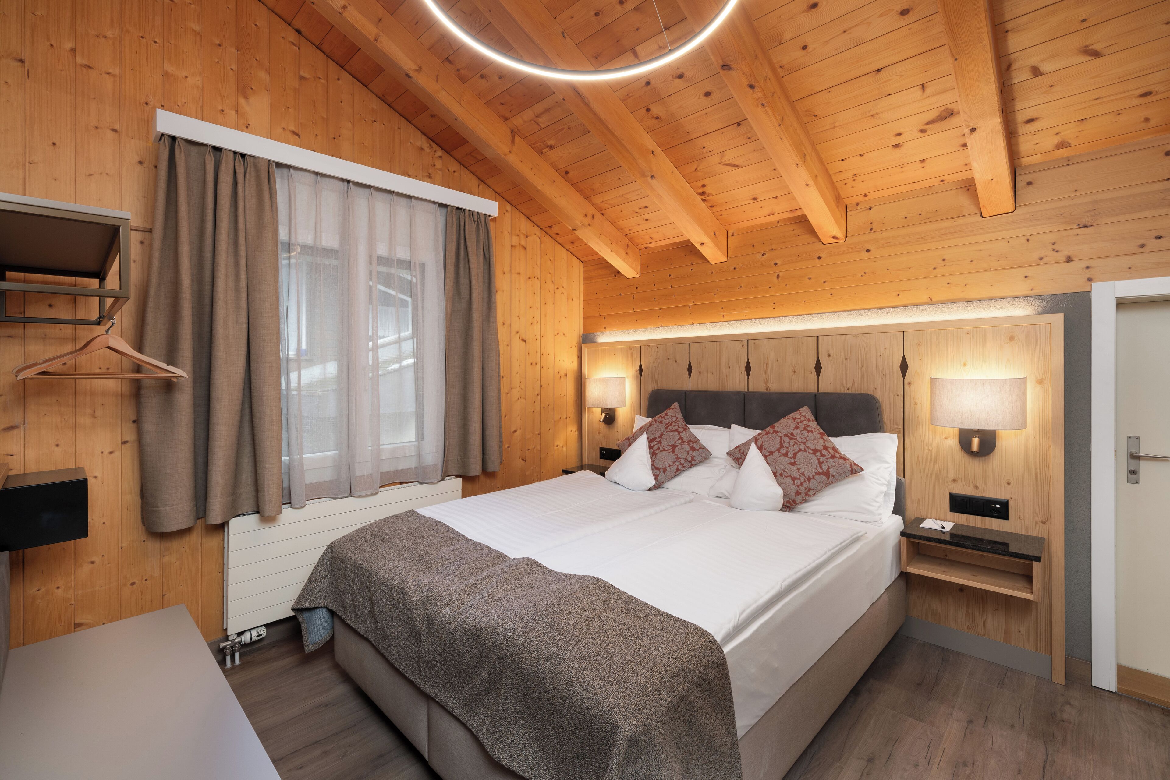 Un dormitorio con paneles de madera, una cama, mesitas de noche y un perchero.