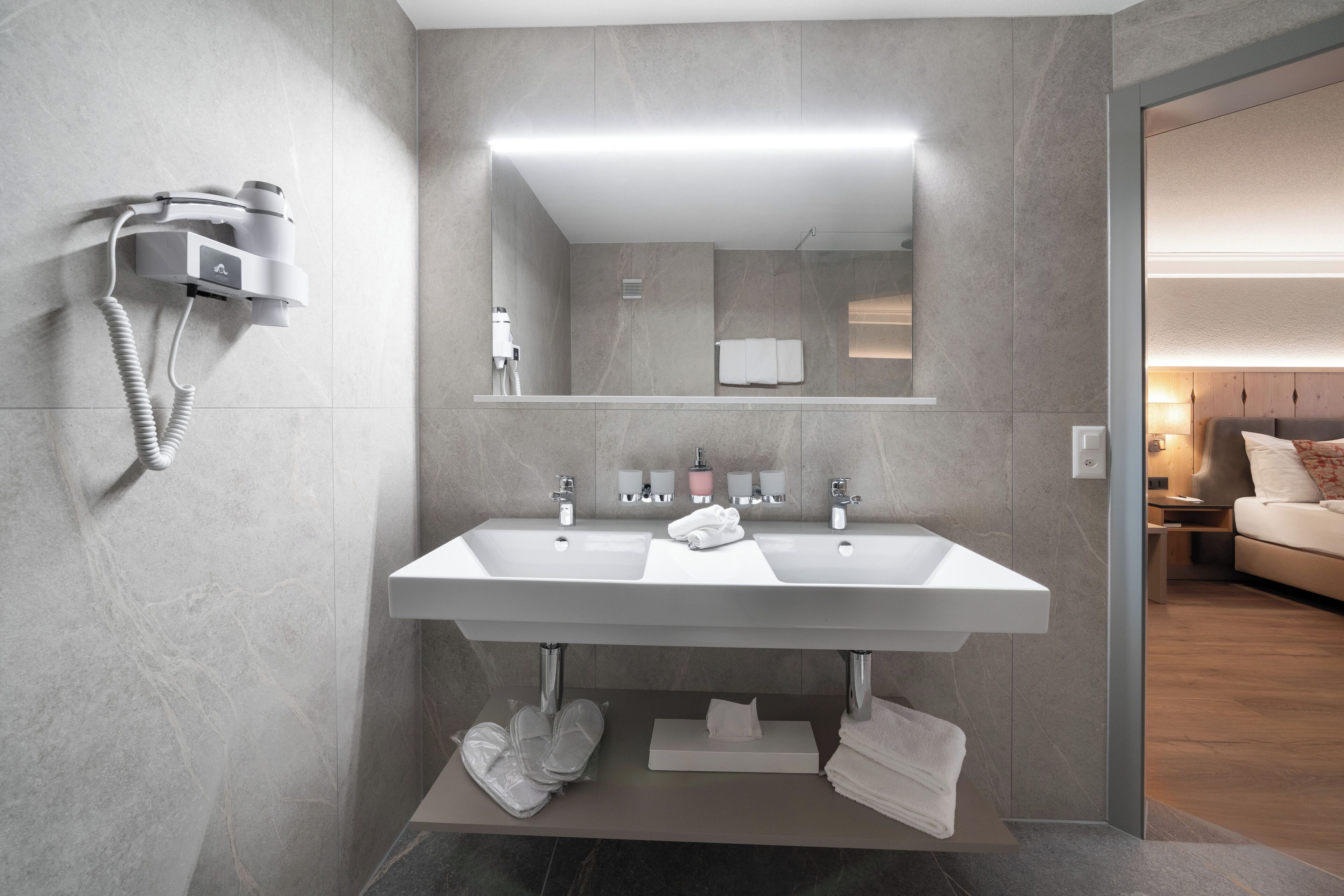 Ein modernes Badezimmer mit zwei Waschbecken, einem Föhn und einem Spiegel.