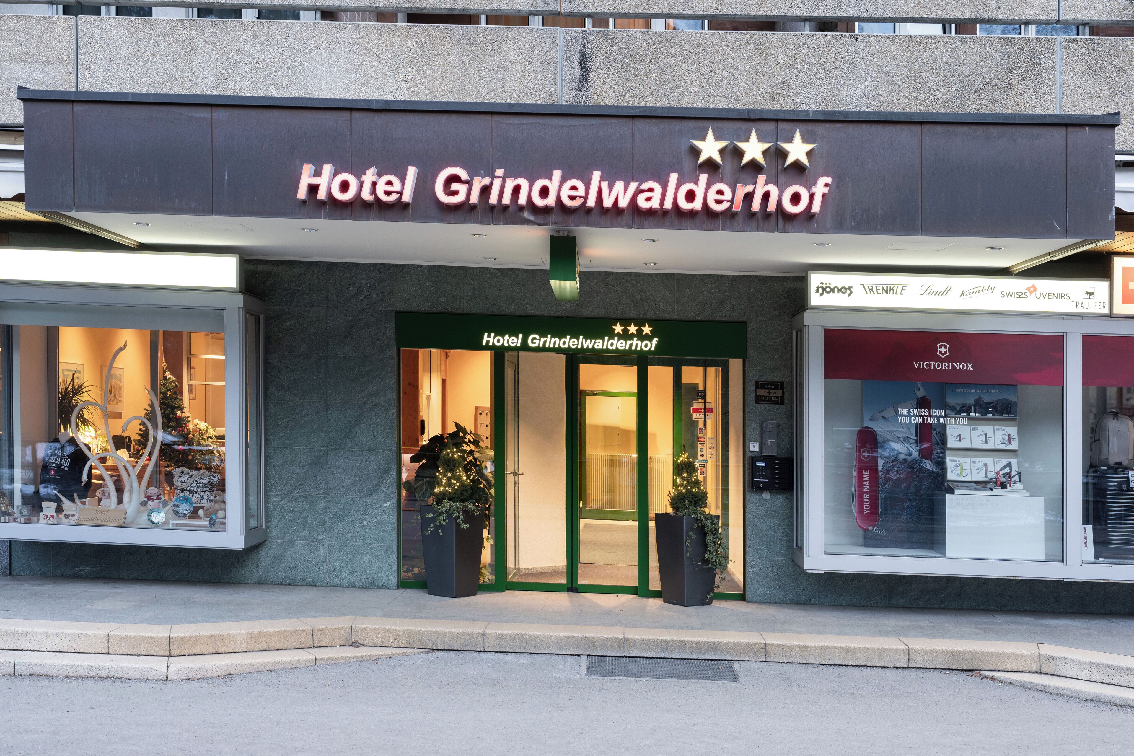 Hotel Grindelwaldhof with a prominent sign, large windows, and a green entrance.