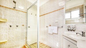 Un baño moderno con cabina de ducha de vidrio, un lavabo blanco y un espejo grande.