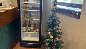 A refrigerator stocked with beverages and a small decorated Christmas tree.