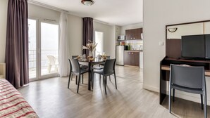 Una habitación de hotel moderna con comedor, cocina y televisor.