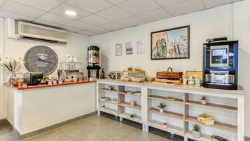 Un espace d’accueil comprenant une horloge, un climatiseur, des œuvres d’art encadrées et une machine à café.