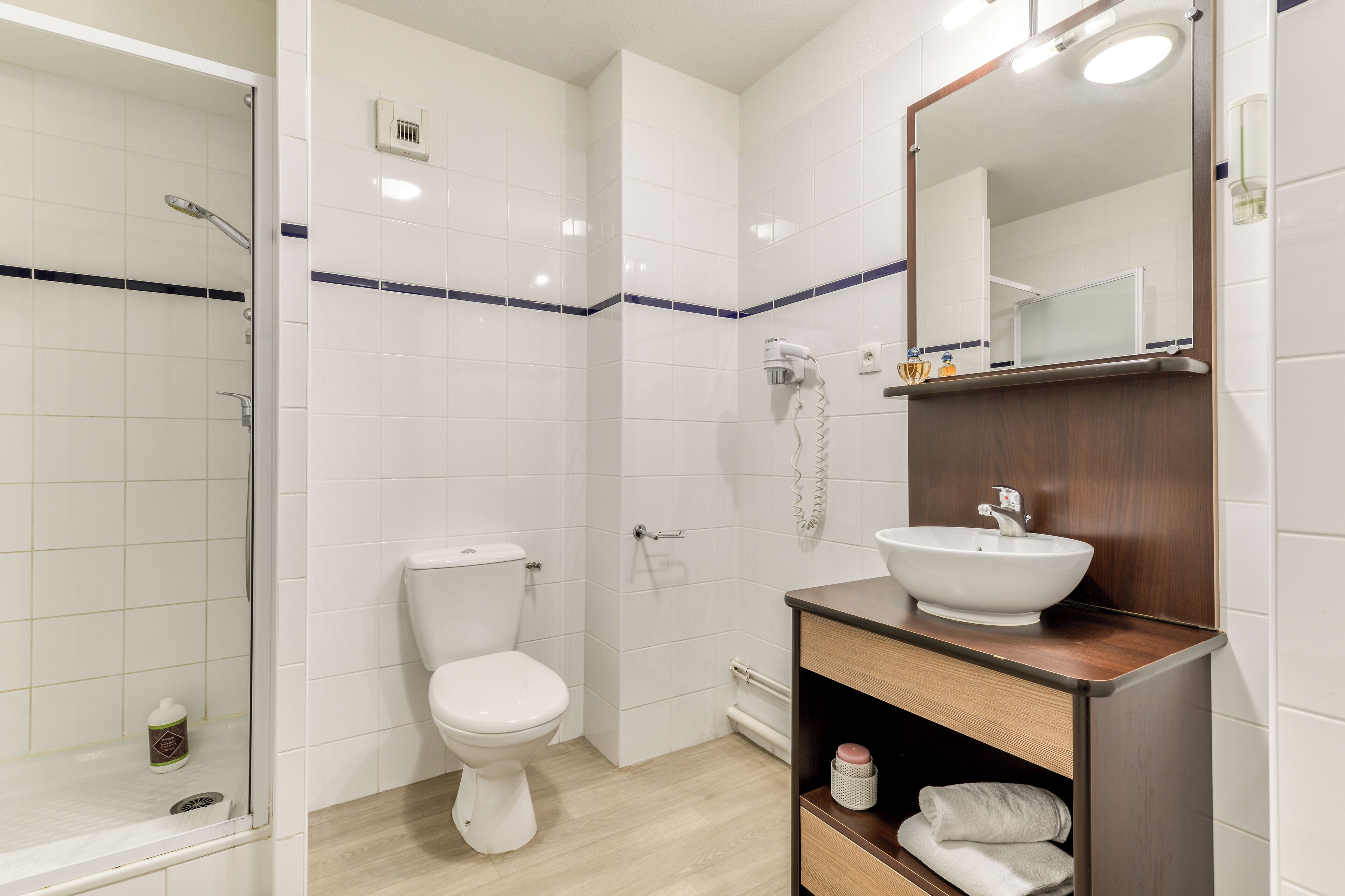 Ein modernes Badezimmer mit Toilette, einer Dusche mit Glastür und einem Holzwaschtisch mit Waschbecken.