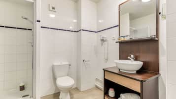 Ein modernes Badezimmer mit Toilette, einer Dusche mit Glastür und einem Holzwaschtisch mit Waschbecken.