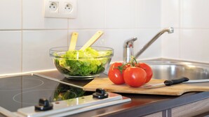 Una cocina con un bol de ensalada, tomates y una tabla de cortar con un cuchillo.