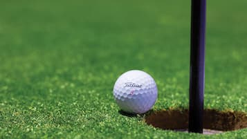 Una pelota de golf cerca del hoyo en un campo verde.