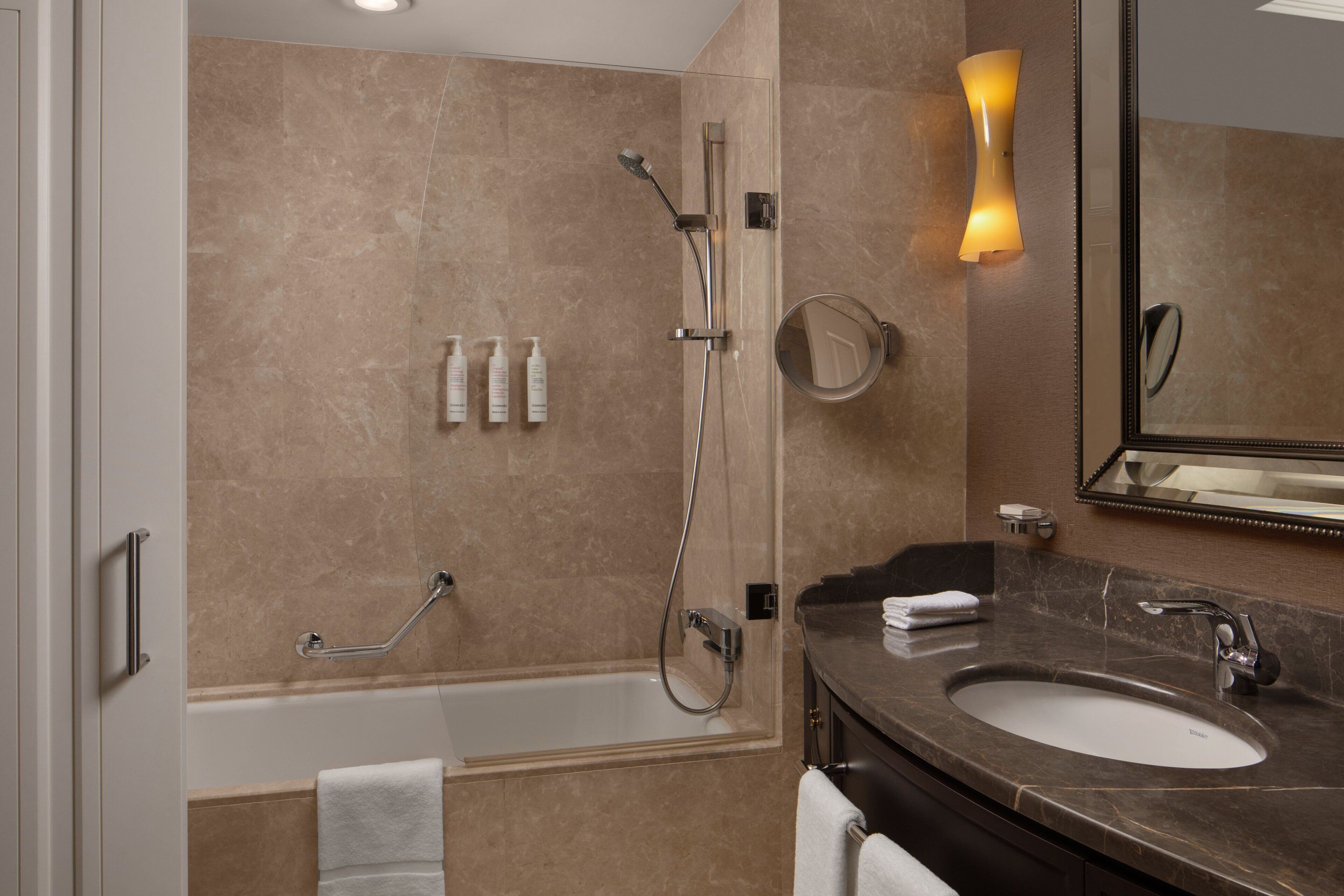 A modern bathroom with a bathtub, a shower, a sink, and a mirror.