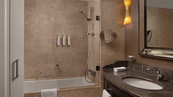 A modern bathroom with a bathtub, a shower, a sink, and a mirror.