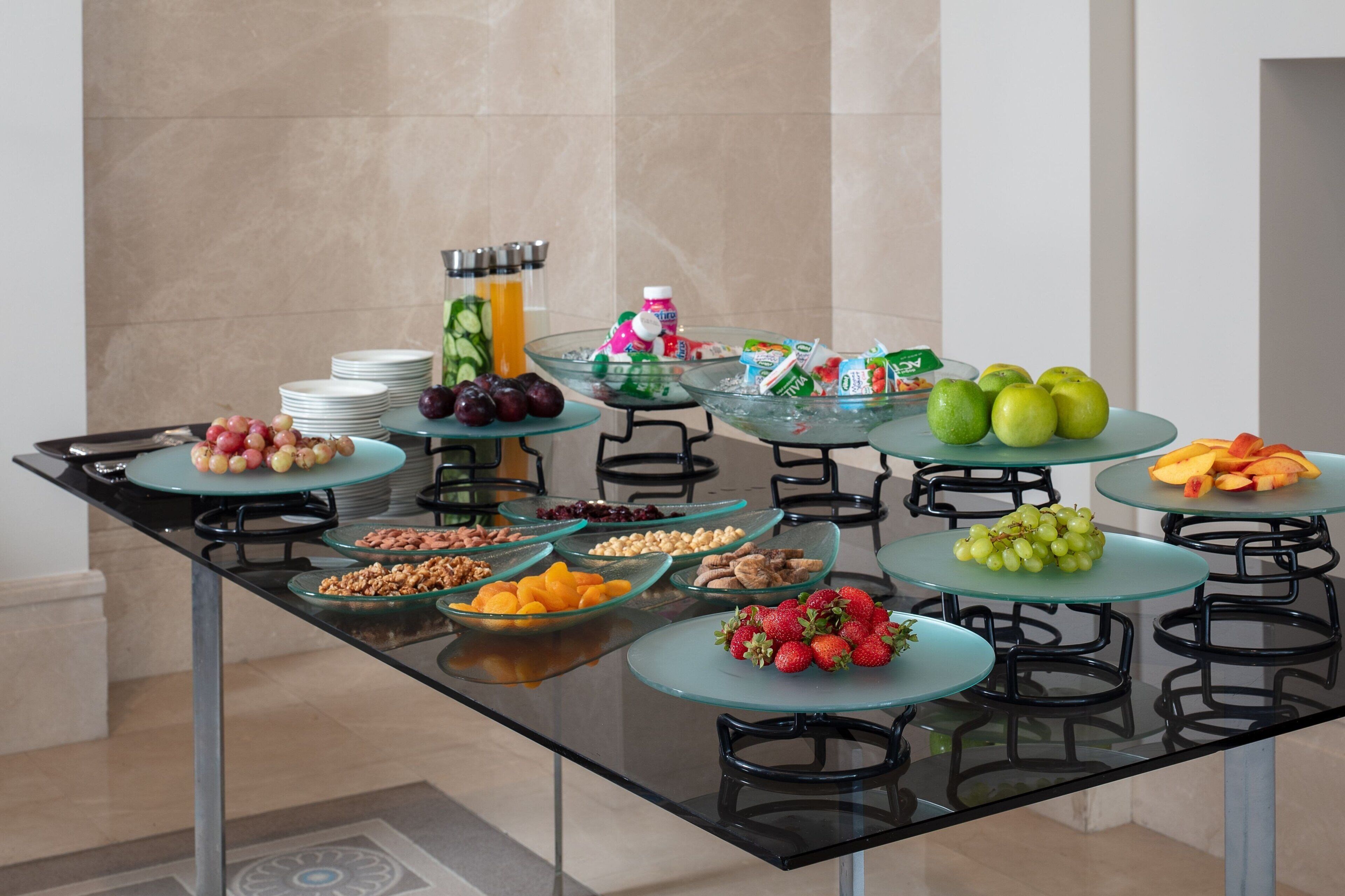 A buffet table with various fruits, vegetables, and beverages.