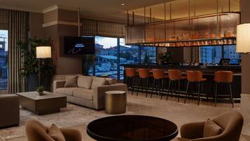 Een moderne hotel lobby met een bar, zitplaatsen en een televisiescherm.