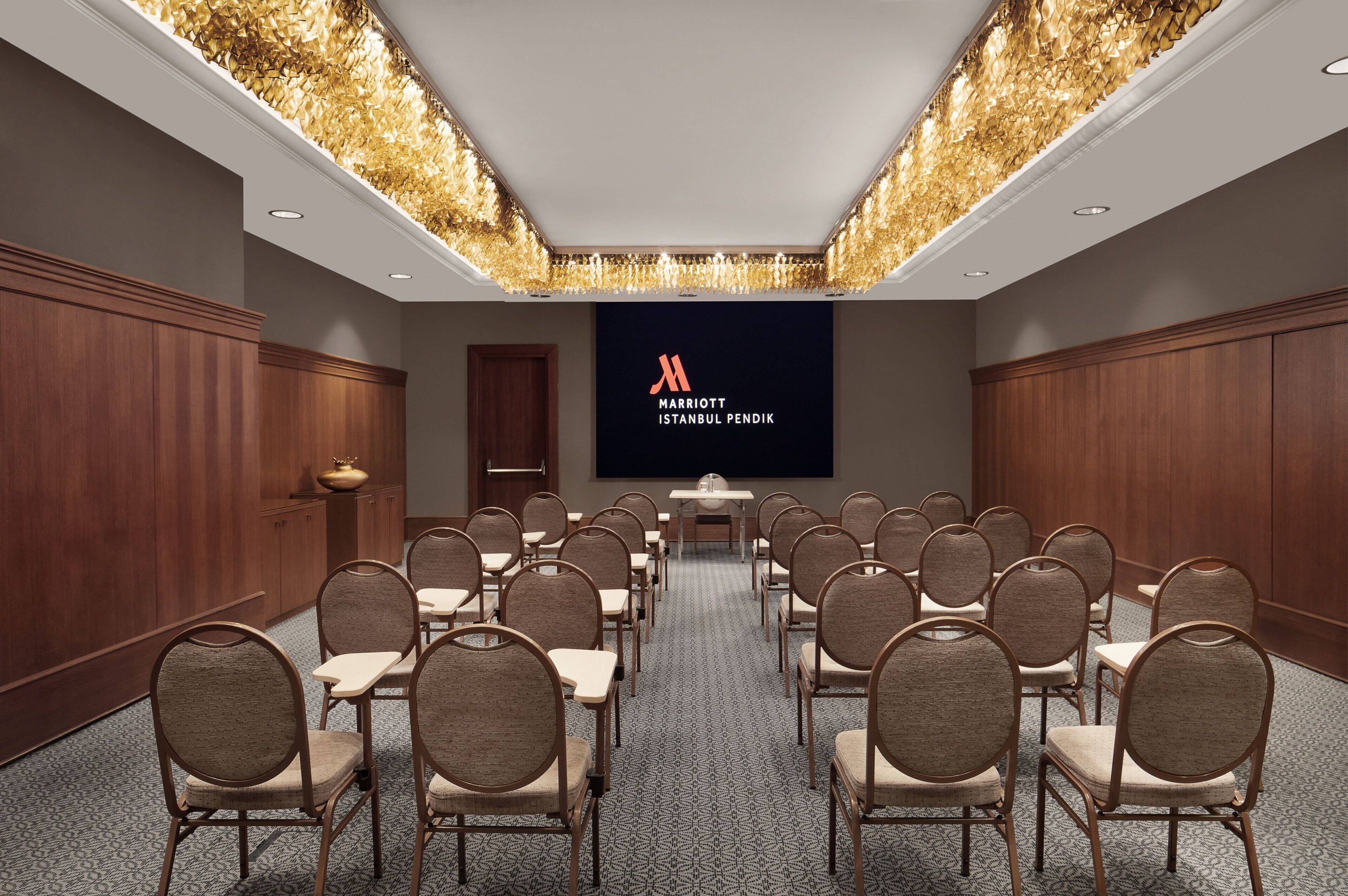 A conference room with rows of chairs and a large screen displaying the Marriott Istanbul Pendik logo.