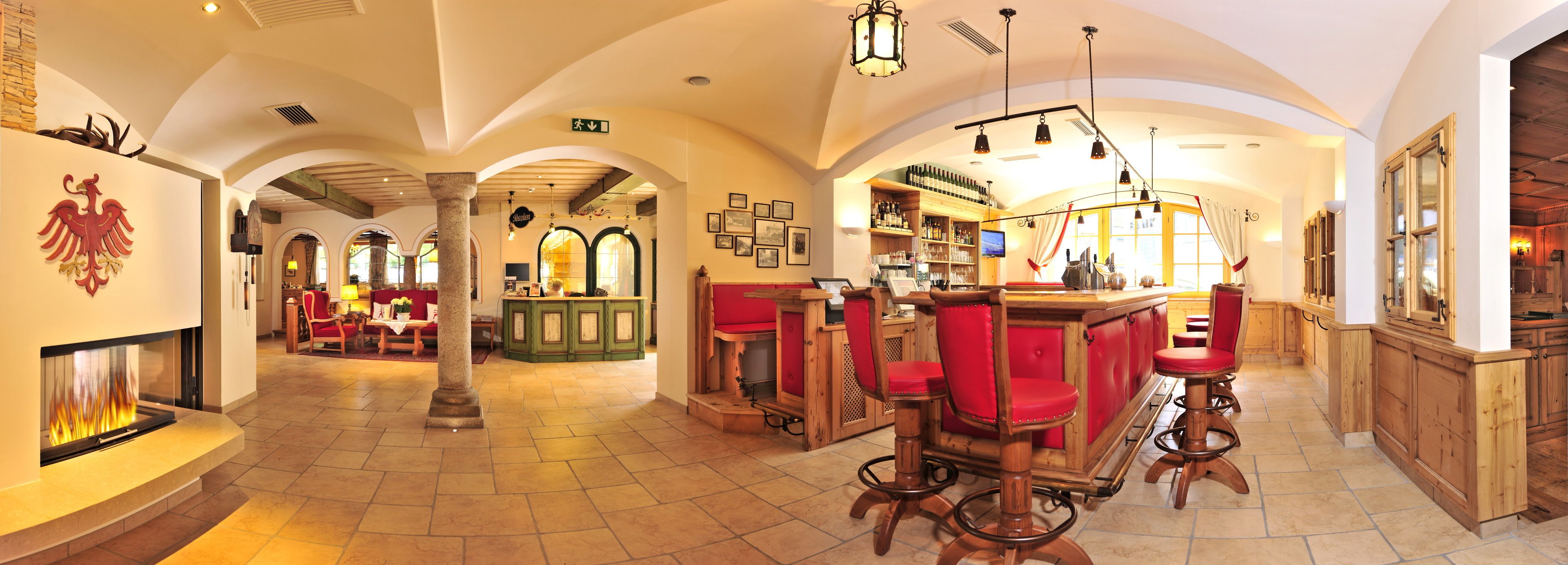 Un amplio vestíbulo de hotel con una zona de bar central, muebles de madera y una chimenea.