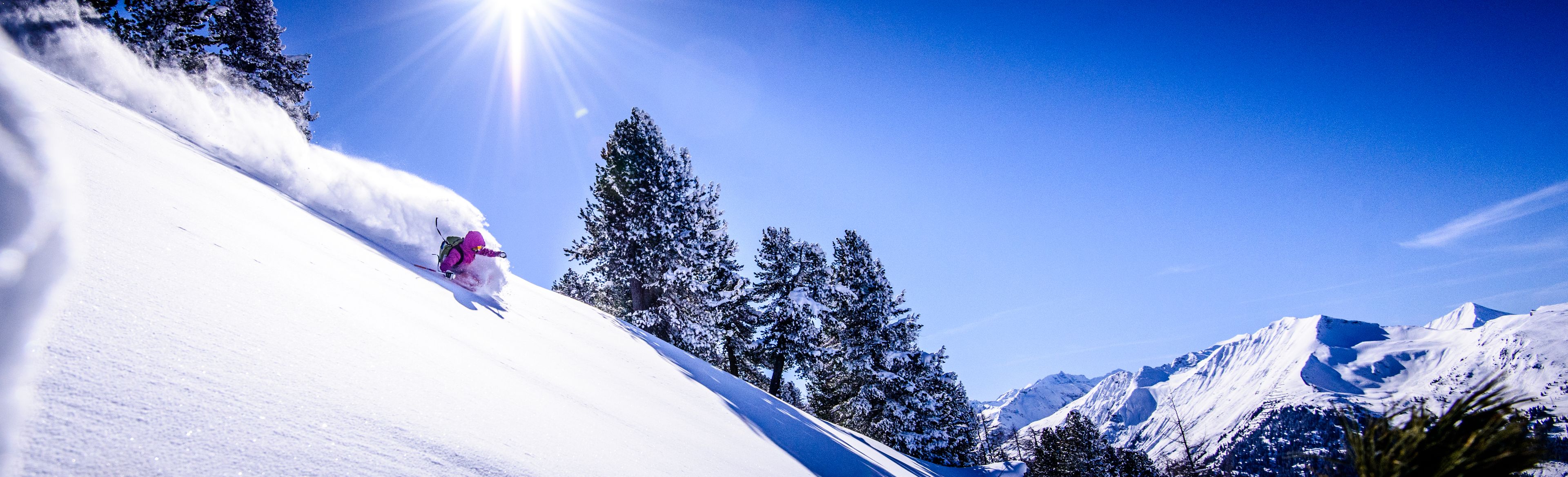 A snowy mountain slope with a skier in motion.