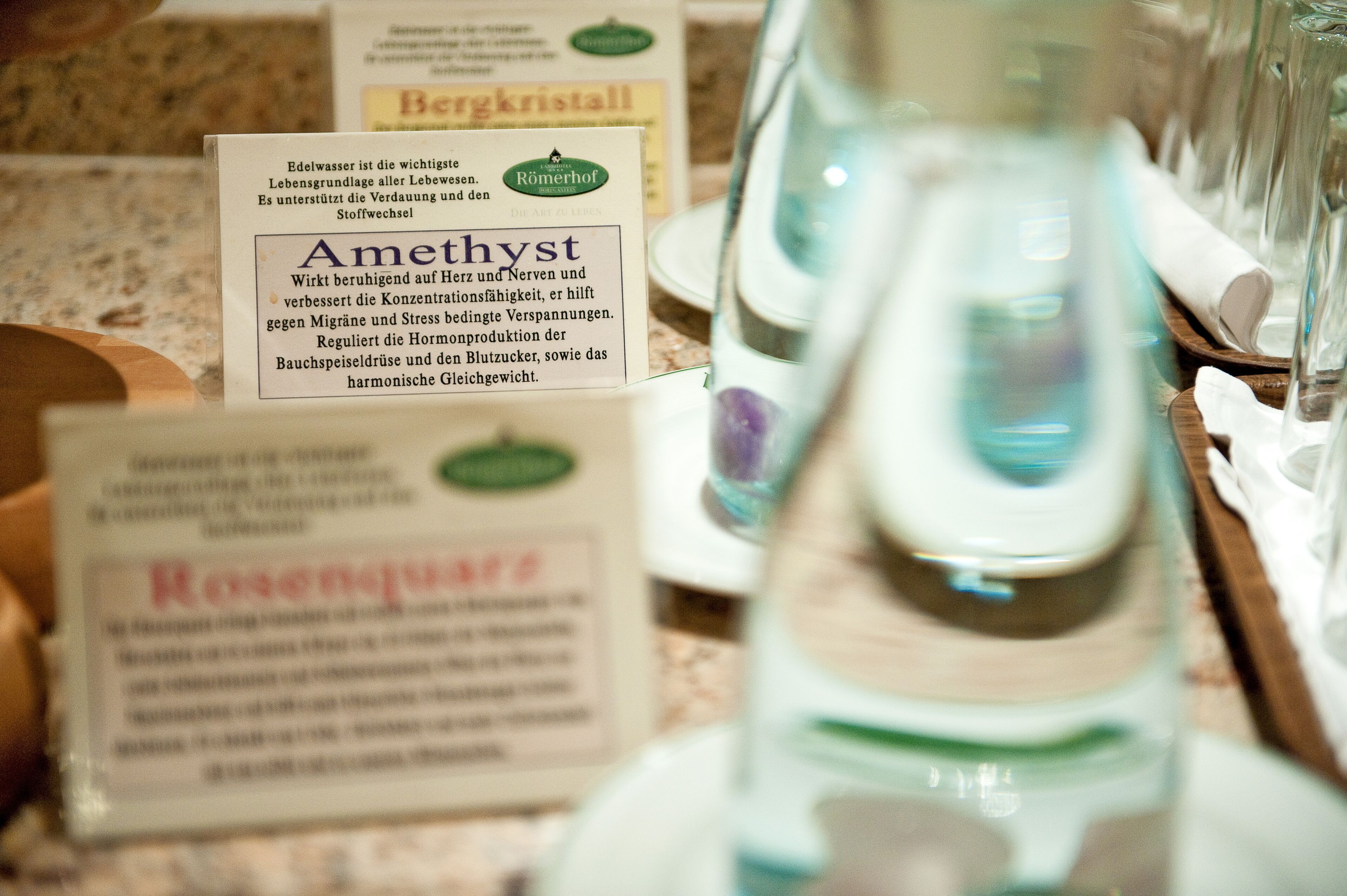 A display of bottled water with labels in German, including brands like Bergkristall and Amethyst.